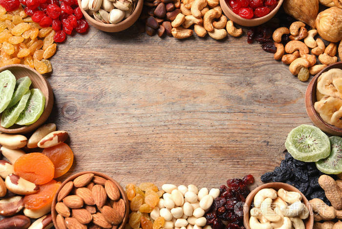 不同干果和坚果的框架在木制背景顶部视图文本空间