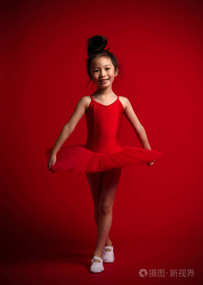 可爱的小女孩芭蕾舞演员芭蕾舞演员在美丽的礼服是在红色跳舞