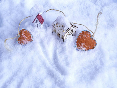 两个有灯光照明的小玩具屋和一双橙色的毛毡在雪地上的概念，季节性寒假情人节圣诞节