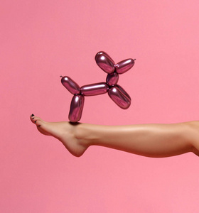 美丽的妇女腿和金属狗气球构成在粉红色
