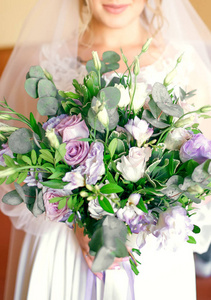 婚礼当天，新娘站在草坪上，手里拿着一束漂亮时尚的花束