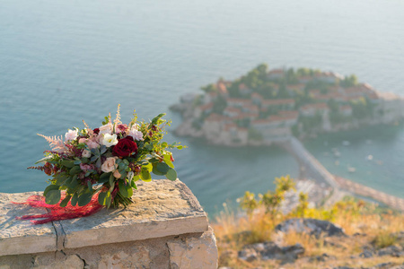 宏伟的婚礼花束站在石子上的 sveti stefan 岛的背景下