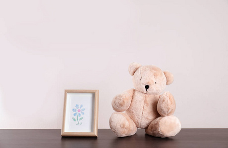 可爱的泰迪熊和框架与可爱的图片在桌子上的光背景空间为文本。 儿童房间单元