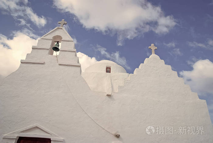 教堂建筑细节在米科诺斯,希腊。教堂钟塔和圆顶与十字架。白色教堂在多云的蓝天上。宗教和概念。地中海岛上的暑假