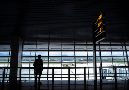 剪影背包游客在机场登机口等待航班进行夏季旅行。