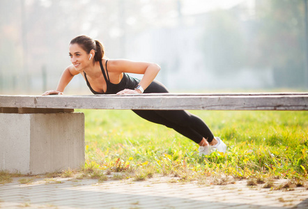 健身。日落时, 田径女子站在户外的木板位置上。体育娱乐和动机的概念