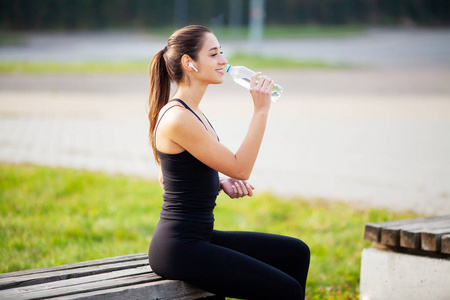 健身。运动和健康生活方式概念在公园锻炼后喝水的妇女