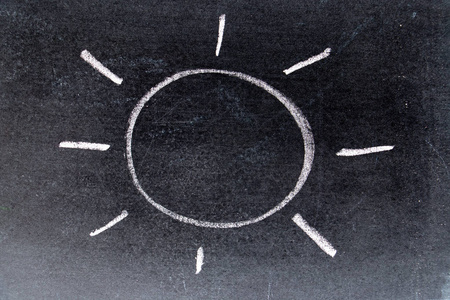 白色粉笔在黑板背景上用光线绘制的太阳手绘照片