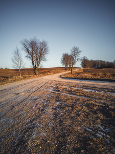 阳光明媚的冬日，空旷的乡村景观，雪的一部分覆盖着地面道路，中间是和平与和谐的照片概念，老式电影的外观。