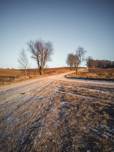 阳光明媚的冬日，空旷的乡村景观，雪的一部分覆盖着地面道路，中间是和平与和谐的照片概念，老式电影的外观。