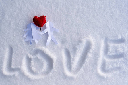 白色雪地背景上，一对手牵着红心的纸男孩和女孩孤独地在纸上写着文字情人节的爱幸福和快乐的概念