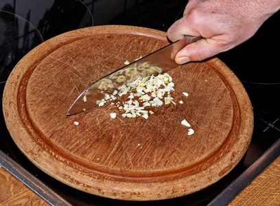 厨师用刀在切割板上切大蒜蒜茸。