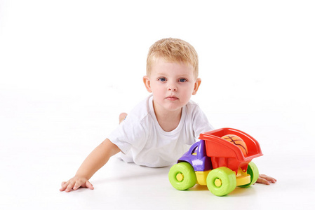 可爱的男孩把玩具车停在地上，隔离在白色上