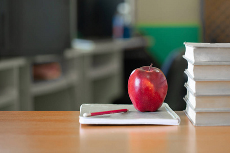 红苹果在一堆书上，纸和铅笔在桌子上的教育理念。