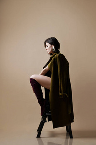 年轻美丽的嬉皮士女孩坐在的内衣, 棕色春天夹克和现代时尚皮靴思考