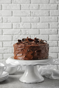 站在白色砖墙附近的桌子上，放着美味的自制巧克力蛋糕。 文本空间