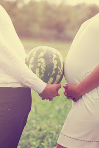 年轻漂亮的怀孕夫妇手里拿着西瓜