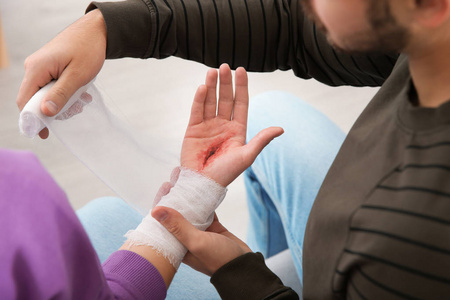 年轻人在家里给受伤的手臂包扎. 急救照片