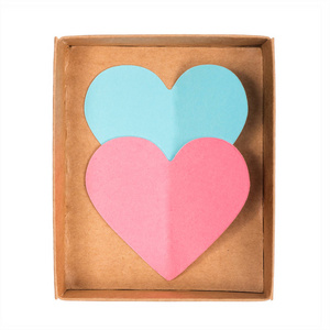 蓝色和粉红色纸心脏在打开纸板箱查出在白色背景