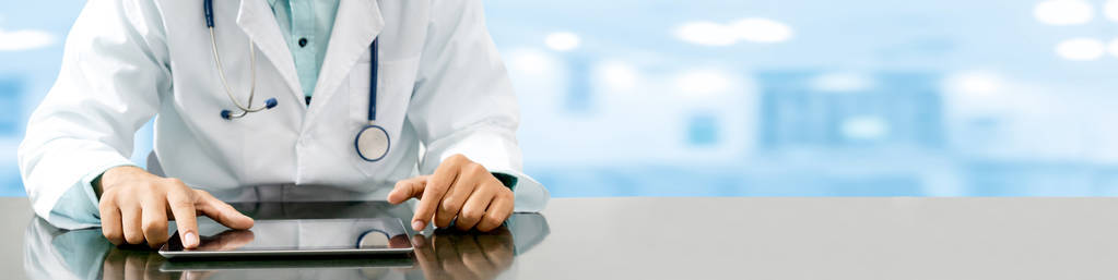 男医生坐在医院办公室里的平板电脑桌前。医疗保健人员和医生服务。