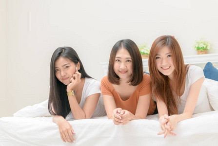 三个漂亮女孩的肖像在床上微笑，生活方式和放松