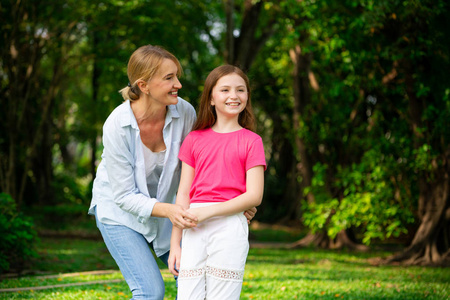 轻松快乐的母亲和小女儿在户外公共公园。 父母和孩子的概念。