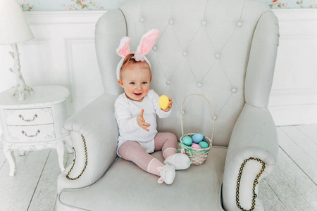 复活节穿兔子耳朵的小女孩。 女孩拿着篮子，在家里装饰彩蛋，玩复活节彩蛋狩猎。 节日庆典春节概念