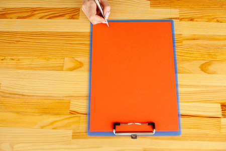 办公室手拿着一个带红色纸的文件夹在木桌的背景上。Copyspace。文本位置