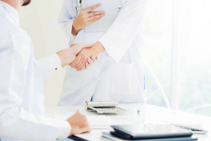 医院的医生向另一位医生握手,展示了专业医护人员的成功和团队合作.