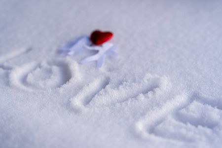 白色雪地背景上，一对手牵着红心的纸男孩和女孩孤独地在纸上写着文字情人节的爱幸福和快乐的概念