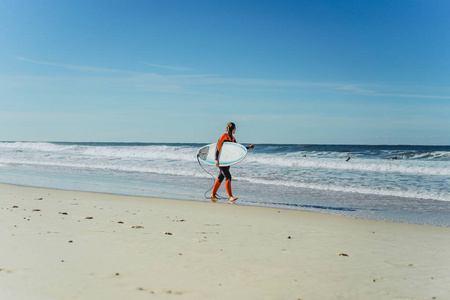 在海洋海岸冲浪女孩穿着湿衣服与冲浪板纳扎尔葡萄牙。