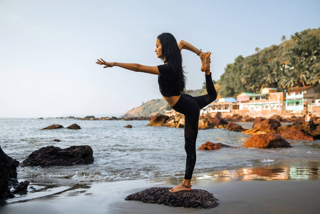 ung frisk kvinna utvar yoga p stranden vid solnedgngen