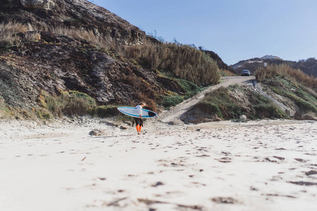 在海洋海岸冲浪女孩穿着湿衣服与冲浪板纳扎尔葡萄牙。