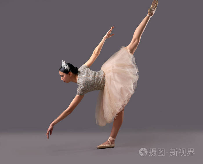 芭蕾舞演员弯腰在演播室里抬起一条腿
