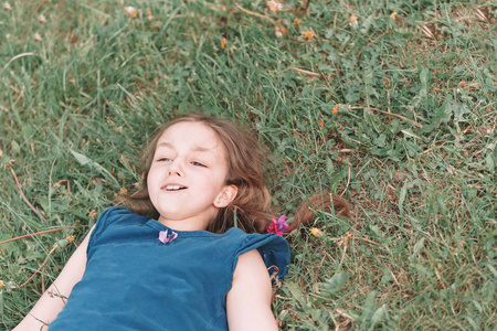 在一个温暖的夏日里, 小女孩躺在绿草上