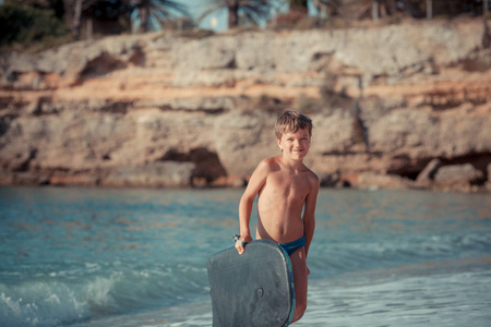 快乐可爱男孩在海上冲浪板户外游泳的肖像。