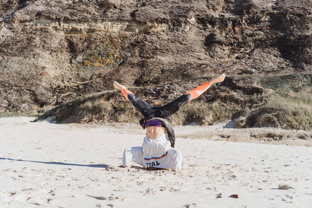 在海滩上做瑜伽的女孩站在她的头上。