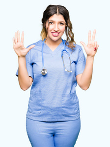 年轻的成年医生女士穿着医疗制服，用8号手指举着，微笑着自信和快乐。