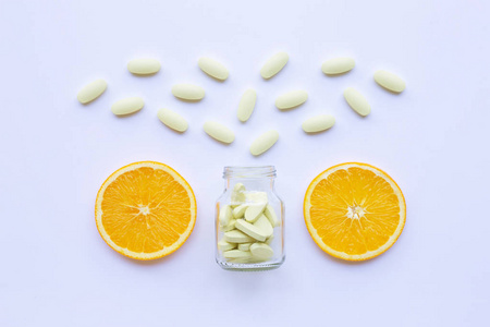 维生素C瓶和药丸与橙色水果在白色背景。
