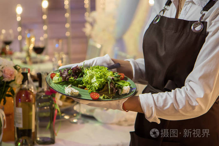 女服务员配菜菜盘,提供宴会桌. 餐厅餐饮服务.