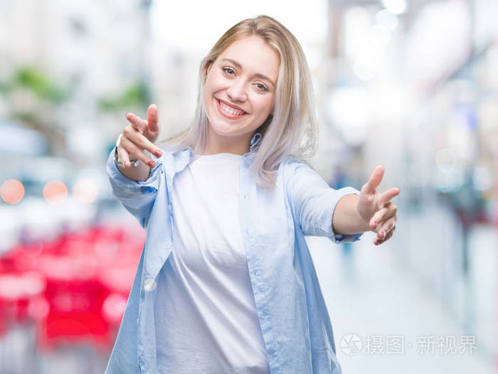 年轻的金发女人在孤立的背景下,看着相机,张开双臂拥抱微笑.