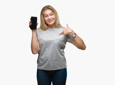 年轻的白种人女人在孤立的背景上显示智能手机屏幕，惊讶的脸指向自己