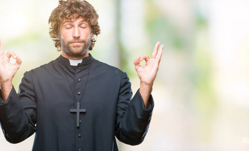 英俊的西班牙裔天主教牧师男子在孤立的背景下放松和微笑，闭上眼睛，用手指做冥想手势。 瑜伽概念。
