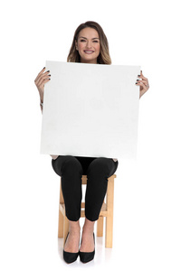 女商人拿着空的白板，坐在白色背景的木椅上