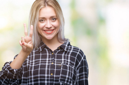 年轻的金发女子在孤立的背景显示和指着第二个手指，同时微笑自信和快乐。