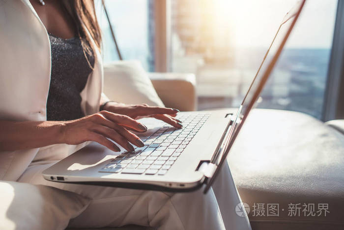 女性手在笔记本电脑键盘上打字特写