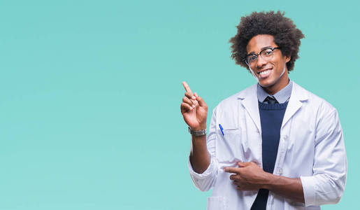 非洲美国医生科学家男子在孤立的背景上，脸上挂着一个大大的微笑，用手和手指指向一边，看着相机。