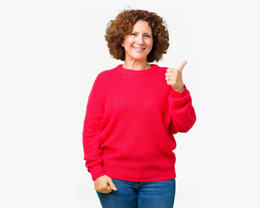 美丽的中间年龄更高的高级妇女红色冬季毛衣，在孤立的背景下，用手做快乐的竖起大拇指的手势。 赞许的表情看着相机显示成功。