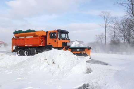 一辆有犁的大汽车从雪中清除了道路。橙色货物专用设备正在冬季与元素搏斗。消除暴风雪的影响。交通困难。冷冻水。