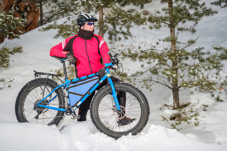一个在冬天骑胖自行车的年轻人。 胖轮胎自行车。